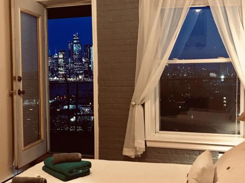 a bedroom with a window with a view of a city at Mega Stunning Skyline View - APT 4-5 Combination - 6 Bedroom - Sleeps 25 - 15 mins to NYC in Union City