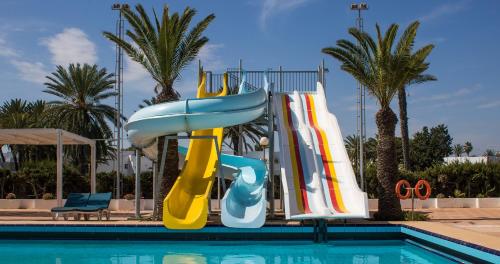 a water slide in a swimming pool next to a swimming pool at El Mouradi Club Selima in Port El Kantaoui