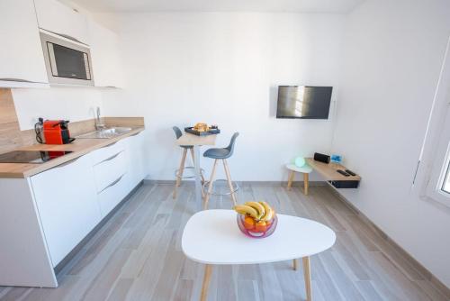 - une cuisine blanche avec un bol de fruits sur une table dans l'établissement Joli Studio proche Promenade des Anglais, à Nice