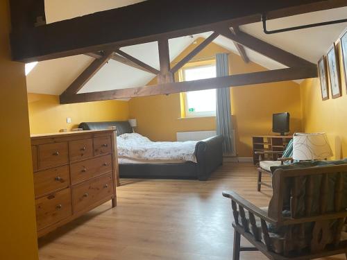 a bedroom with a bed and a dresser and a window at Ye Old Sun Inn, Barn Studio in Bilbrough