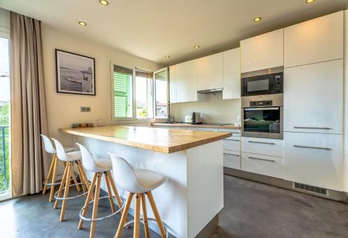 une cuisine avec des armoires blanches et des tabourets de bar dans l'établissement Floralies B l Bright & Parking l Shellter Rentals, à Saint-Tropez