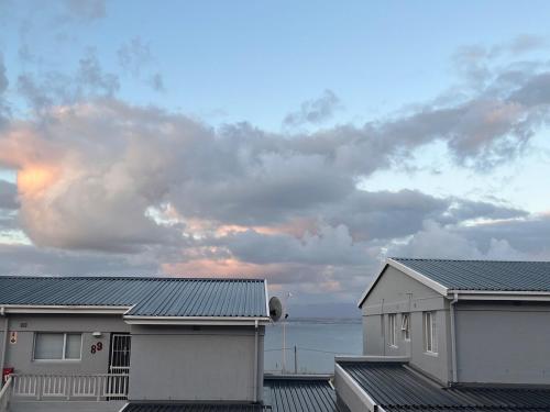 a cloudy sky with two buildings in front of the water at Suite at Bay in Mossel Bay