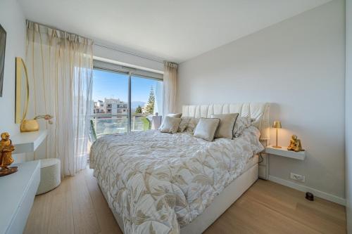 une chambre blanche avec un grand lit et une fenêtre dans l'établissement Panoramic Sea View flat - Pool in the Residence, à Nice