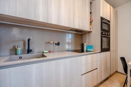 une cuisine avec des armoires en bois et un évier dans l'établissement Studio Blanqui l Design & Cozy l Shellter Rentals, à Saint-Tropez