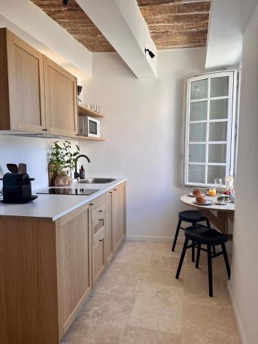 une cuisine avec des armoires en bois, une table et une fenêtre dans l'établissement Le Paon l Old Town & AC l Shellter Rentals, à Saint-Tropez