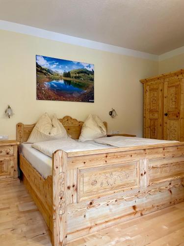 a large wooden bed in a bedroom with a painting on the wall at Pension Waldheim in Mauterndorf