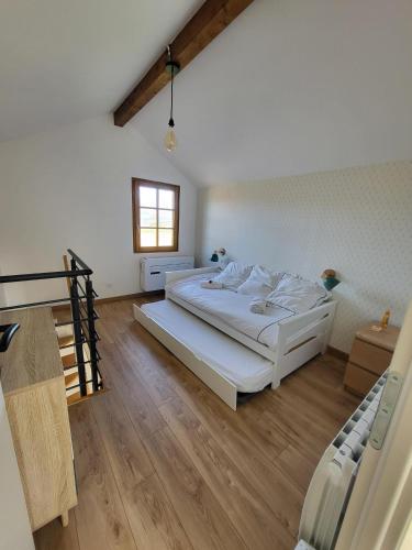 une chambre avec un grand lit blanc et une fenêtre dans l'établissement Le Grangeon, à Belley