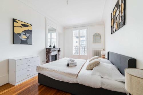 - une chambre avec un grand lit aux murs blancs dans l'établissement Appartement 3 Pieces au Coeur du 19e - 4P, à Paris