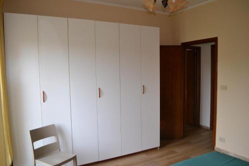 a bedroom with white cabinets and a chair at Nichi & Matti Iemmolo's Guest House in Campofelice di Roccella