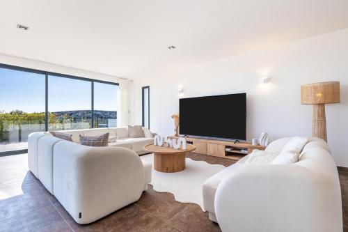 Il comprend un salon doté d'un mobilier blanc et d'une télévision à écran plat. dans l'établissement Luxueuse Villa pour huit personnes, piscine et vue sur le Golf, à Juvignac