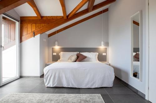 a bedroom with a large white bed with wooden ceilings at The Cliff Amalfi Coast - Apartment 1 in Pianillo