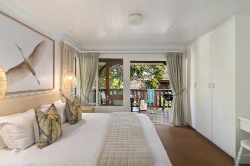 a bedroom with a large white bed with white pillows at Knysna - Fern Cottage in Knysna
