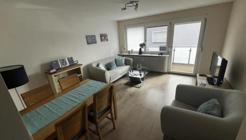 a living room with a table and a couch and a television at Wohnung direkt am See, 58 qm in Reichenau