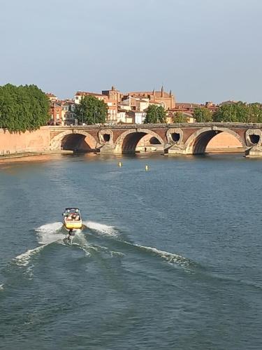 a boat in the water in a river with a bridge at Chambre d'hote la passerelle in Mazamet