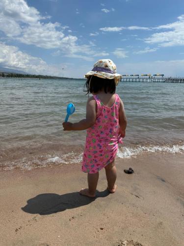 a little girl standing on the beach with a ball at Алые Паруса in Cholpon-Ata