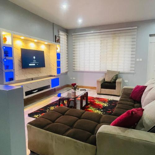 a living room with a couch and a tv at Mus homes in Accra