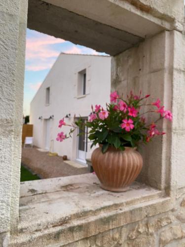a vase with pink flowers sitting on a ledge at Les gîtes des Lauriers roses Chambre privée Île d Aix in Geay