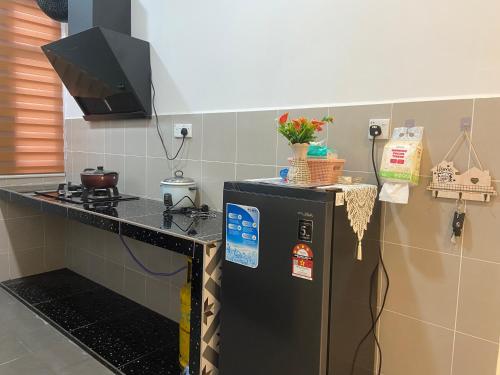 a kitchen with a stove and a refrigerator at Homestay DNailah in Kampong Jelatang