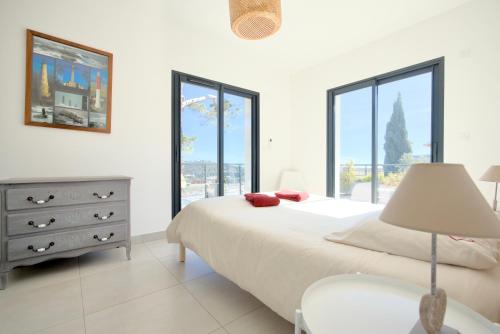 - une chambre avec un lit, une commode et des fenêtres dans l'établissement Le Cap Marlou, vue mer exceptionnelle, à Saint-Mandrier-sur-Mer