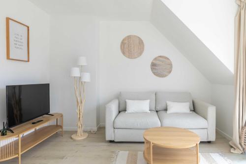a white living room with a couch and a tv at The Ocean Breeze 1 in De Haan