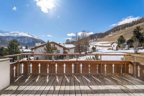 a wooden deck with a view of a snowy mountain at Chalet St Moritz in Madulain
