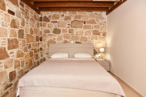 a bed in a room with a stone wall at Kentos Charming Stone Escape Near Fishing Harbor in Katarráktis