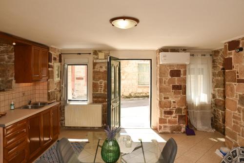 a kitchen with a sink and a glass table at Kentos Charming Stone Escape Near Fishing Harbor in Katarráktis