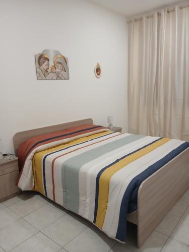 a bed with a colorful blanket on it in a bedroom at MaGa House in Catania