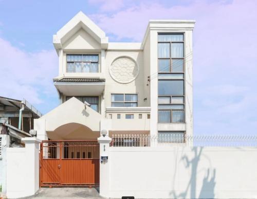 a large white house with a red gate at Charming 3-Storey house near BTS Onnut Station in Bangkok