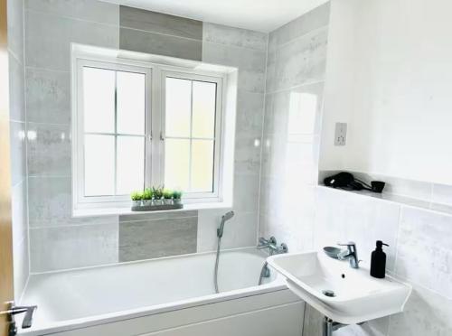 baño blanco con bañera, lavabo y ventana en New Build Luxury Home in Ashford, en Willesborough
