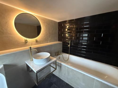 a bathroom with a sink and a tub and a mirror at Lyons Woodlands Hall in Ruthin
