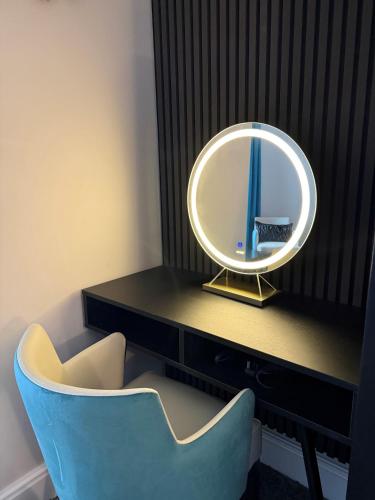 a mirror sitting on a desk with a blue chair at Lyons Woodlands Hall in Ruthin