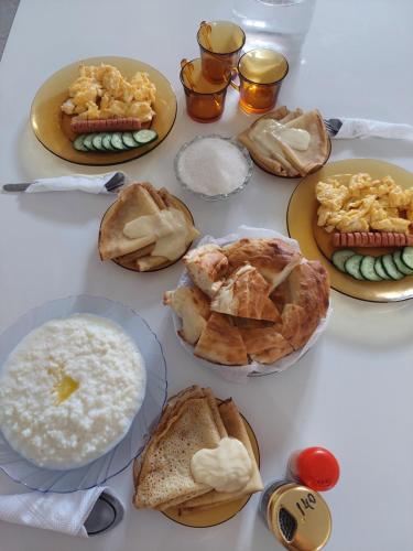 a table with plates of breakfast foods on it at Алые Паруса in Cholpon-Ata