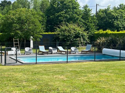 Une clôture avec des chaises et une piscine dans la cour dans l'établissement Maisons Les Gites de l'Odet, à Clohars-Fouesnant