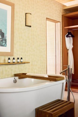 a bathroom with a white tub and a mirror at Hermitage Bay - All Inclusive in Saint Johnʼs