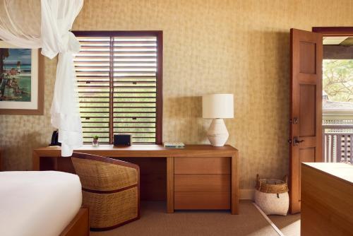 a bedroom with a bed and a desk with a window at Hermitage Bay - All Inclusive in Saint Johnʼs