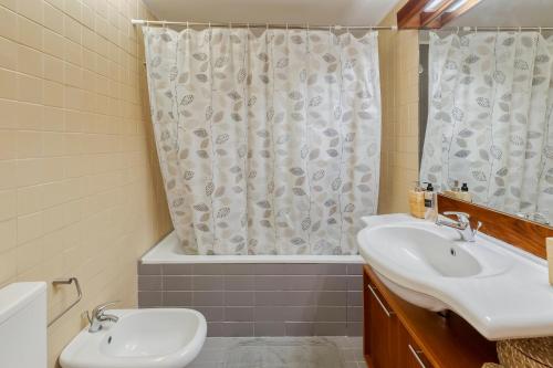 Un baño con lavabo y cortina de ducha. en Três Marias, en Tróia