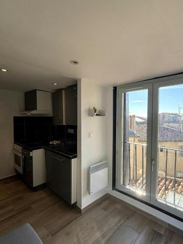 une cuisine avec une grande fenêtre offrant une vue dans l'établissement F2 Toits Ecusson 4 pers. Eglise St Anne 5 min Com, à Montpellier