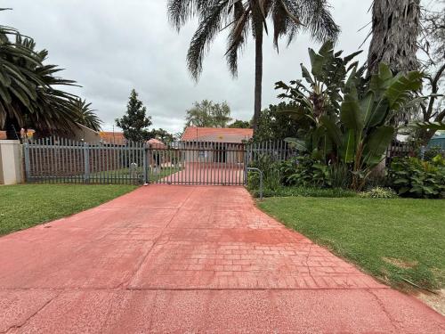 a red brick walkway with a gate in a yard at Flora Haven in Polokwane