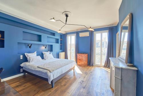 una camera da letto blu con un letto e uno specchio di Le Liberté - Charme & Standing haussmannien avec vue port a Tolone