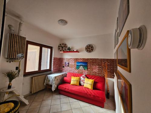 a red couch in a living room with a brick wall at Il Riposo del Viaggiatore by Holiday World in Ternate
