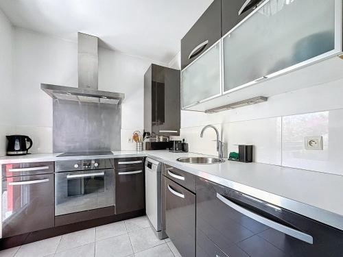 d'une cuisine équipée d'appareils en acier inoxydable et d'un évier. dans l'établissement Le Grand Chelem, Bel appartement secteur Ovalie, à Montpellier