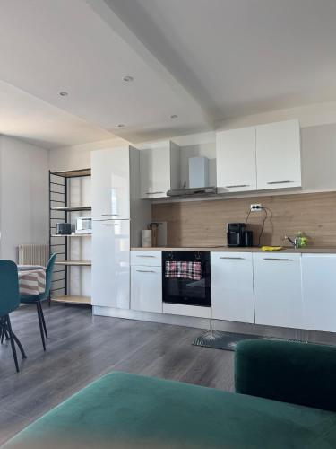 une cuisine avec des armoires blanches et une table et des chaises dans l'établissement Superbe Appart de 4 Chambres, Moderne et Spacieux, à Wattignies