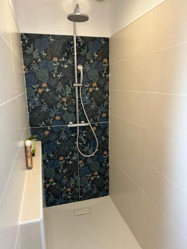La salle de bains est pourvue d'une douche et de papier peint floral noir. dans l'établissement Maison de vacances avec piscine chauffée, à Charron