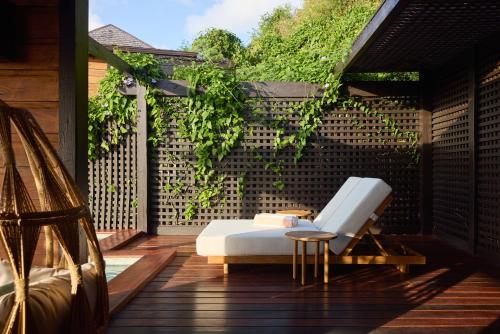 a porch with a bed and a chair on a deck at Hermitage Bay - All Inclusive in Saint Johnʼs