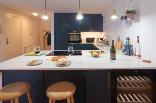 a kitchen with a counter with two chairs and wine glasses at Designer 2 BR Home with Private Balcony in Copenhagen