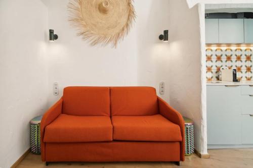 - un canapé orange dans une chambre avec un mur dans l'établissement Studio SEVO l Central l Shellter Rentals, à Saint-Tropez