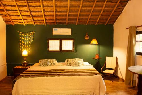 a bedroom with a bed and a green wall at Posada de las Huellas in Loreto