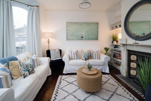 a living room with two white couches and a fireplace at Firefly House in Cowes