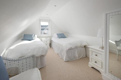 een witte slaapkamer met 2 bedden en een spiegel bij Firefly House in Cowes